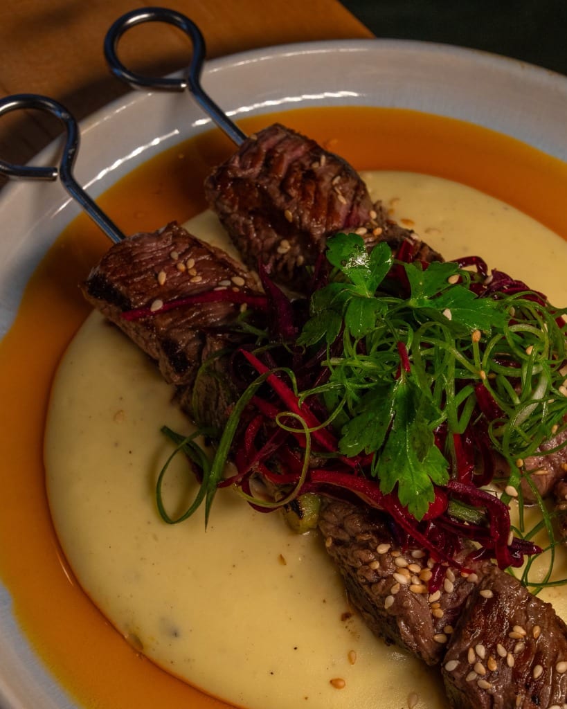 Grilled meat skewers served with puree and fresh herbs